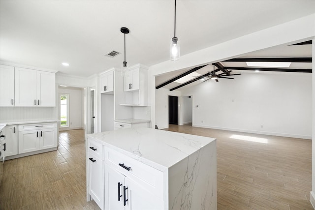9711 Braewick Dr, Houston, TX 77096 - kitchen with light stone countertops, white cabinetry, a kitchen island, light wood-type flooring, and recessed lighting