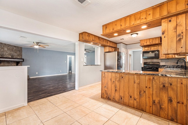 306 Hickory Ridge Dr, Shenandoah, TX 77381 - kitchen featuring black appliances, a ceiling fan, brown cabinetry, and a peninsula