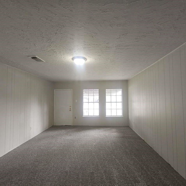 6523 Hanley Ln, Houston, TX 77016 - unfurnished room featuring carpet flooring, a textured ceiling, and wood walls