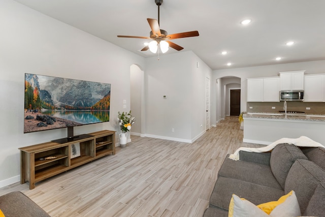10005 Red Beadtree Pl, Conroe, TX 77385 - living room featuring arched walkways, light wood-style flooring, a ceiling fan, and recessed lighting