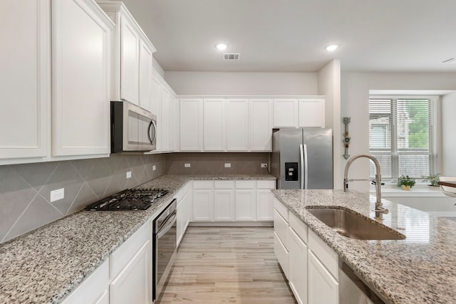 10005 Red Beadtree Pl, Conroe, TX 77385 - kitchen featuring stainless steel appliances, white cabinets, tasteful backsplash, light wood finished floors, and recessed lighting