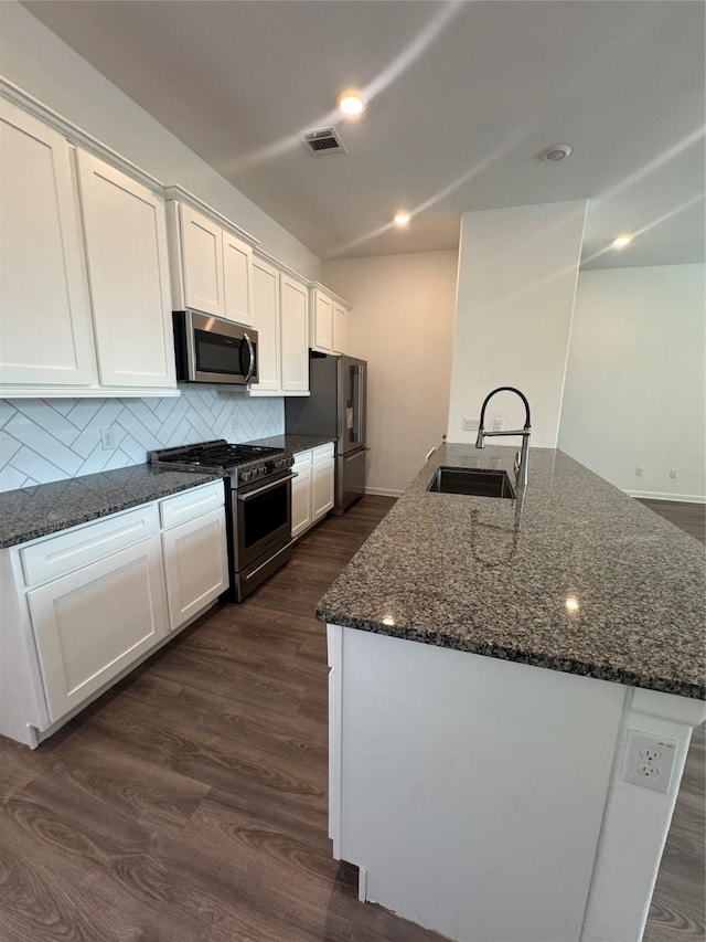 4727 Glen Isle Dr, Houston, TX 77009 - kitchen with high end appliances, white cabinets, dark wood-style floors, tasteful backsplash, and dark stone counters