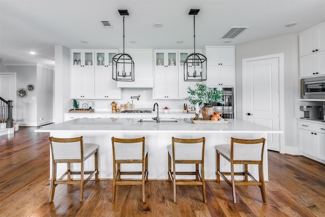 3239 Caney Dr, Katy, TX 77493 - kitchen with glass insert cabinets, stainless steel appliances, light countertops, an island with sink, and recessed lighting