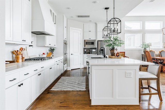 3239 Caney Dr, Katy, TX 77493 - kitchen with custom range hood, stainless steel appliances, light countertops, and white cabinets