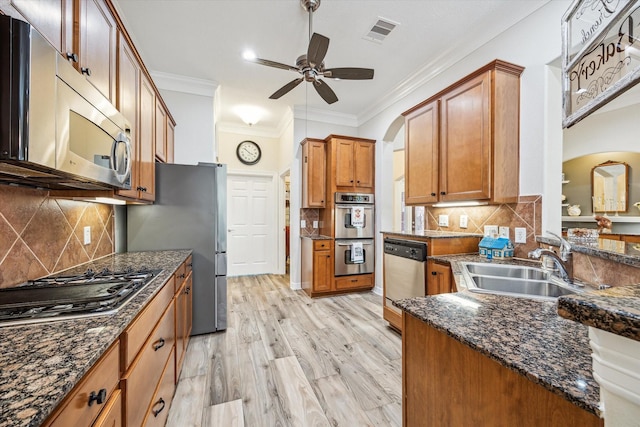 1607 N Primavera Dr, Pearland, TX 77581 - kitchen featuring appliances with stainless steel finishes, arched walkways, crown molding, ceiling fan, and brown cabinetry