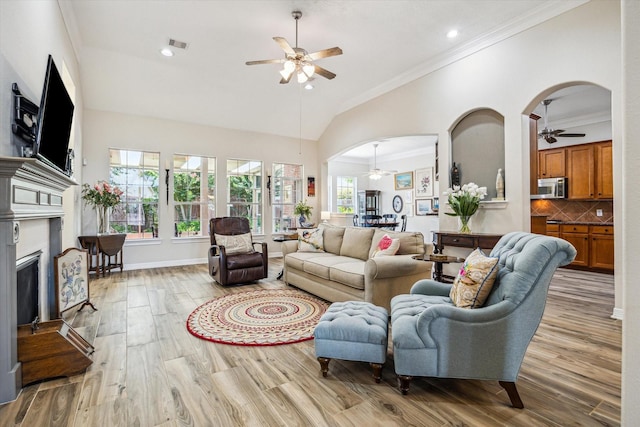 1607 N Primavera Dr, Pearland, TX 77581 - living room with a ceiling fan, ornamental molding, a fireplace, wood finished floors, and arched walkways