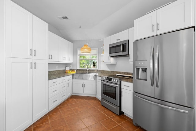 20559 Red Bud Ct, Thornton, TX 76687 - kitchen with appliances with stainless steel finishes, dark tile patterned floors, white cabinetry, vaulted ceiling, and dark stone countertops
