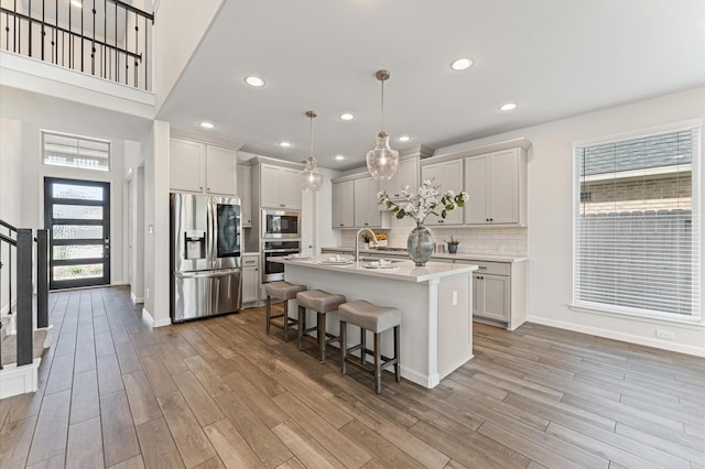 29622 Sterling Knoll Dr, Fulshear, TX 77441 - kitchen with stainless steel appliances, light countertops, light wood-type flooring, a breakfast bar, and recessed lighting
