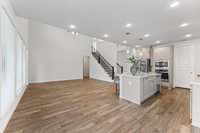 29622 Sterling Knoll Dr, Fulshear, TX 77441 - kitchen with stainless steel appliances, light wood finished floors, a breakfast bar, light countertops, and a kitchen island with sink