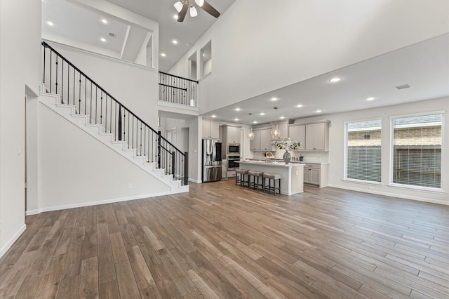 29622 Sterling Knoll Dr, Fulshear, TX 77441 - unfurnished living room featuring a ceiling fan, wood finished floors, stairway, a high ceiling, and recessed lighting
