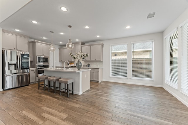 29622 Sterling Knoll Dr, Fulshear, TX 77441 - kitchen featuring stainless steel appliances, light wood-type flooring, gray cabinetry, a kitchen breakfast bar, and recessed lighting