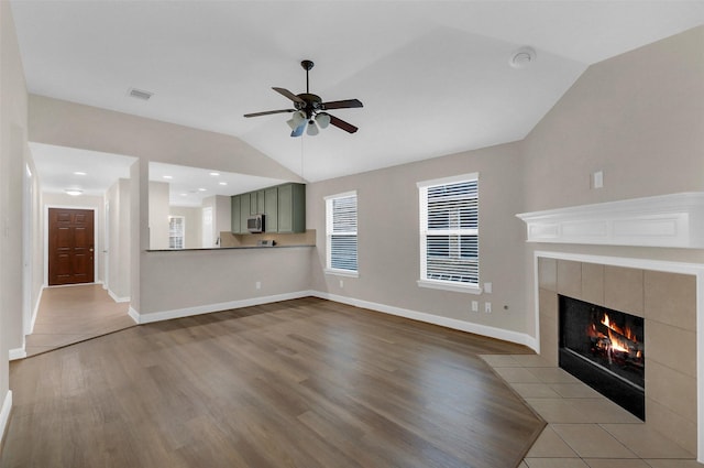 10143 Rose Willow Ln, Brookshire, TX 77423 - unfurnished living room with lofted ceiling, a ceiling fan, a tiled fireplace, and wood finished floors