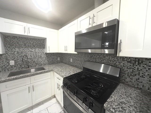 9013 Lugary Dr, Houston, TX 77074 - kitchen with stainless steel appliances, light marble finish flooring, white cabinets, light stone countertops, and backsplash