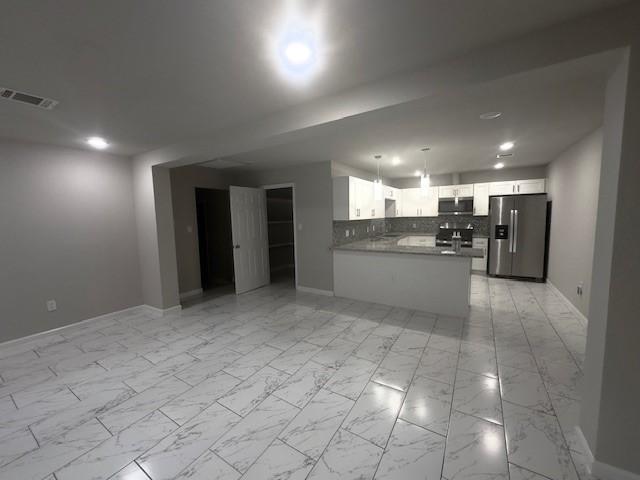 9013 Lugary Dr, Houston, TX 77074 - kitchen with appliances with stainless steel finishes, open floor plan, decorative backsplash, white cabinets, and a peninsula