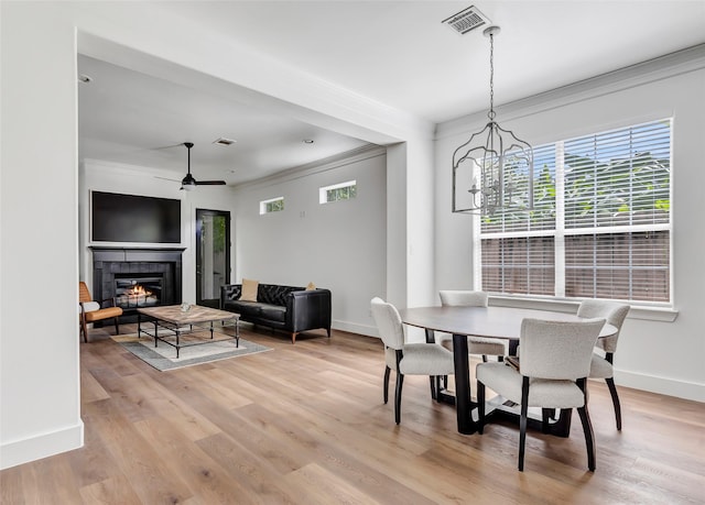 5406 Darling St Unit A, Houston, TX 77007 - dining space with crown molding, a tiled fireplace, light wood-style flooring, ceiling fan, and a chandelier