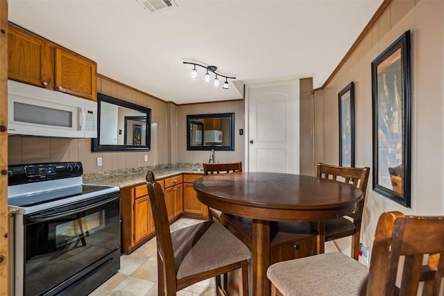 374 W Lake Shore Dr, Livingston, TX 77351 - kitchen with black range with electric stovetop, white microwave, brown cabinets, and light stone counters