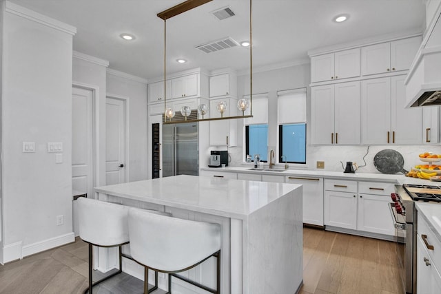 3502 Dorset Cliff Ln, Houston, TX 77055 - kitchen featuring premium appliances, crown molding, custom exhaust hood, white cabinetry, and light countertops