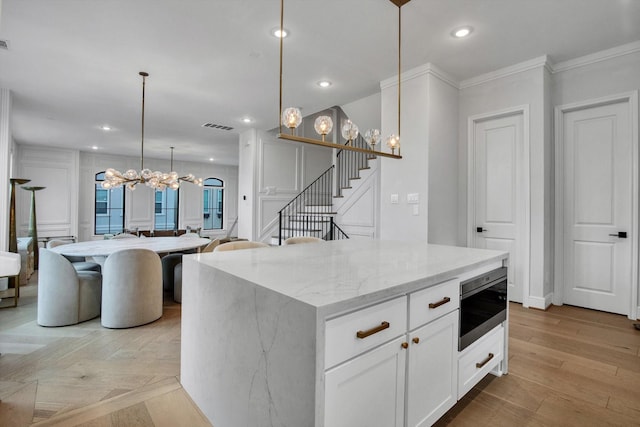 3502 Dorset Cliff Ln, Houston, TX 77055 - kitchen with a chandelier, a decorative wall, a center island, light stone countertops, and white cabinets