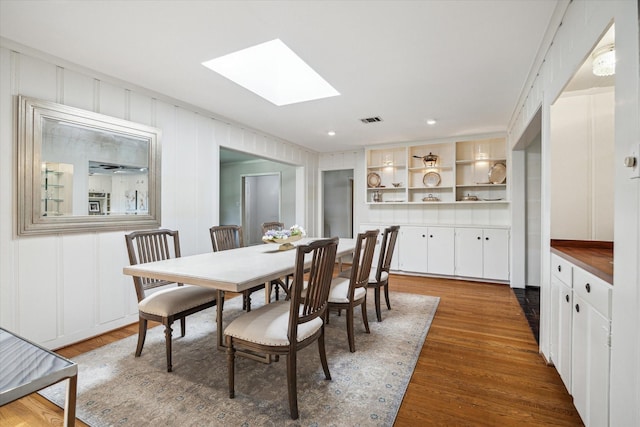 6249 Piping Rock Ln, Houston, TX 77057 - dining room featuring a skylight, a decorative wall, wood finished floors, and recessed lighting