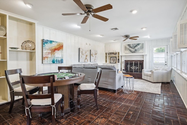 6249 Piping Rock Ln, Houston, TX 77057 - dining room with ceiling fan, brick floors, a fireplace, crown molding, and wooden walls