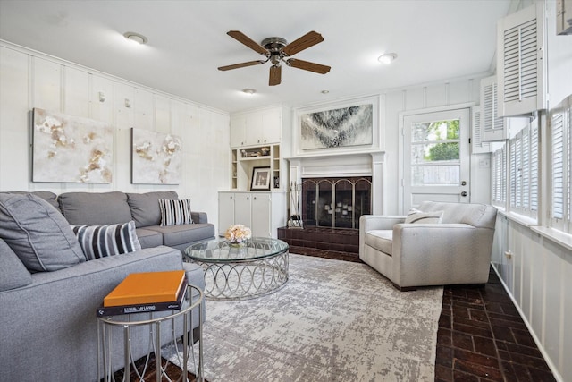 6249 Piping Rock Ln, Houston, TX 77057 - living room with a ceiling fan, a fireplace with raised hearth, ornamental molding, and wood walls