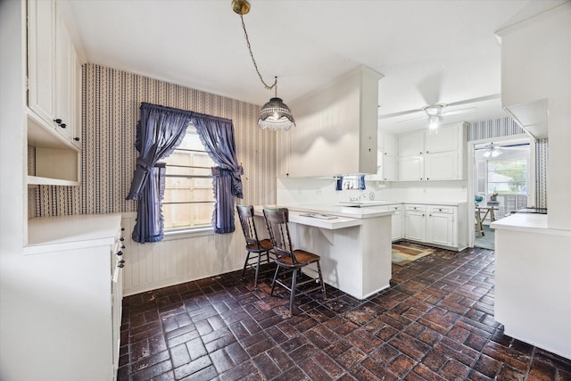 6249 Piping Rock Ln, Houston, TX 77057 - kitchen with brick flooring, wallpapered walls, a peninsula, white cabinets, and a ceiling fan