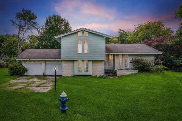 13922 Ambrose St, Houston, TX 77045 - back of property at dusk with a garage, a lawn, brick siding, and concrete driveway