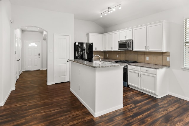 23753 Briar Tree Dr, Porter, TX 77365 - kitchen with appliances with stainless steel finishes, arched walkways, vaulted ceiling, tasteful backsplash, and dark wood-style flooring