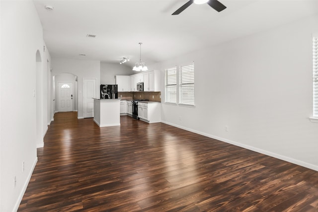 23753 Briar Tree Dr, Porter, TX 77365 - unfurnished living room featuring a ceiling fan, arched walkways, dark wood-style flooring, vaulted ceiling, and a chandelier