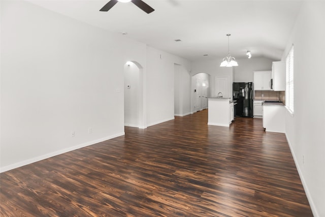23753 Briar Tree Dr, Porter, TX 77365 - unfurnished living room featuring arched walkways, a ceiling fan, dark wood-style floors, a chandelier, and vaulted ceiling