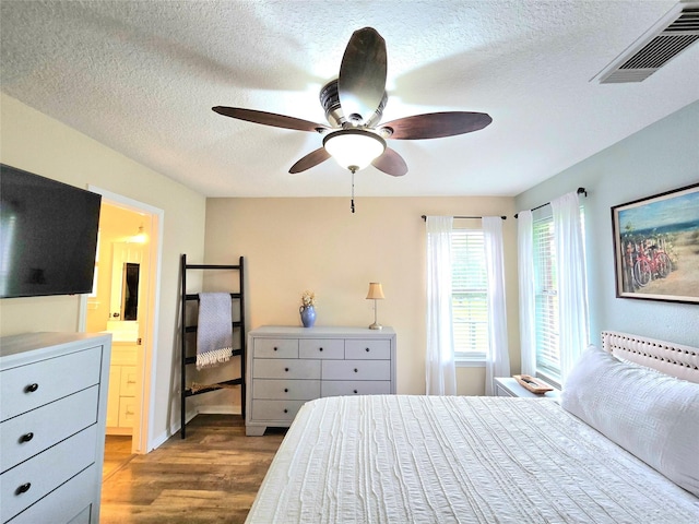 110 Red Bud St, Shepherd, TX 77371 - bedroom featuring wood finished floors, a textured ceiling, ensuite bathroom, and ceiling fan