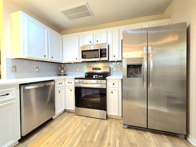 110 Red Bud St, Shepherd, TX 77371 - kitchen featuring appliances with stainless steel finishes, light countertops, light wood finished floors, and white cabinetry