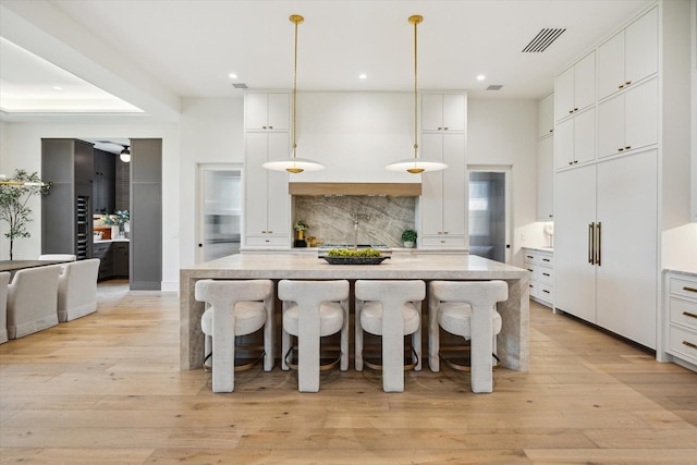 3755 Rice Blvd, Houston, TX 77005 - kitchen featuring a breakfast bar, backsplash, white cabinets, light wood finished floors, and recessed lighting