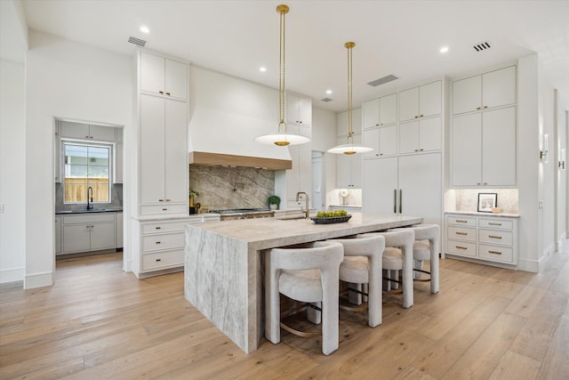 3755 Rice Blvd, Houston, TX 77005 - kitchen with decorative backsplash, a kitchen island with sink, light wood-style floors, and recessed lighting