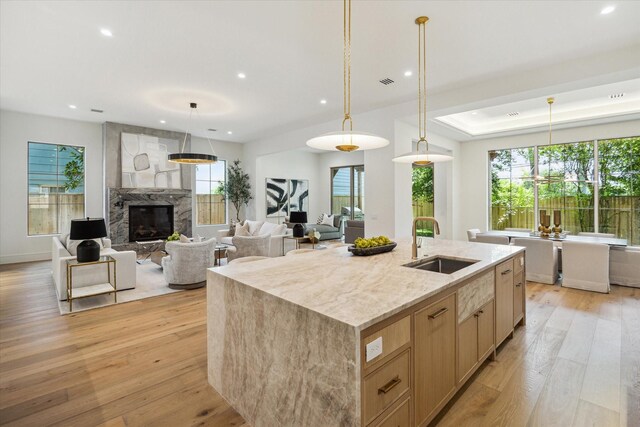 3755 Rice Blvd, Houston, TX 77005 - kitchen with light brown cabinetry, light wood-style floors, recessed lighting, light stone counters, and a kitchen island with sink