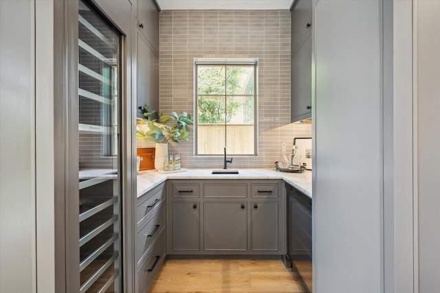 3755 Rice Blvd, Houston, TX 77005 - kitchen with gray cabinetry, decorative backsplash, light stone counters, and light wood finished floors