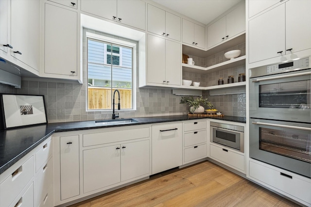 3755 Rice Blvd, Houston, TX 77005 - kitchen featuring stainless steel appliances, light wood-type flooring, backsplash, open shelves, and white cabinetry