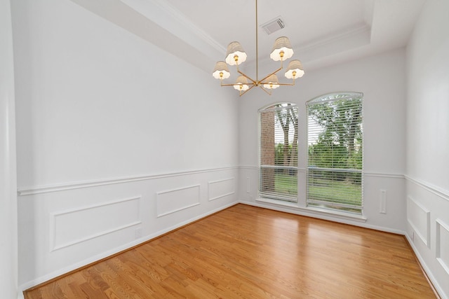 4444 Victory Dr Unit 26, Houston, TX 77088 - empty room with a chandelier, wood finished floors, wainscoting, a tray ceiling, and a decorative wall