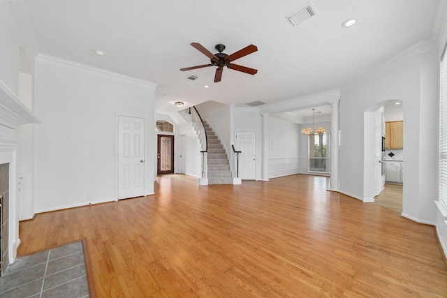 4444 Victory Dr Unit 26, Houston, TX 77088 - unfurnished living room featuring a tile fireplace, arched walkways, a ceiling fan, stairs, and light wood-style flooring
