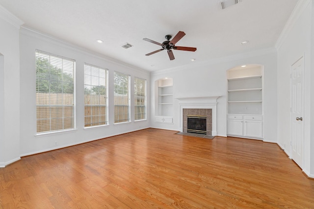 4444 Victory Dr Unit 26, Houston, TX 77088 - unfurnished living room with built in shelves, ornamental molding, a tile fireplace, ceiling fan, and light wood-style floors