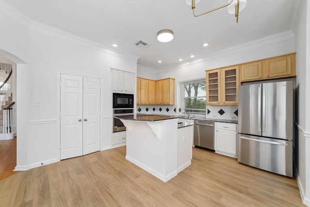 4444 Victory Dr Unit 26, Houston, TX 77088 - kitchen featuring appliances with stainless steel finishes, arched walkways, crown molding, light wood-style flooring, and a center island