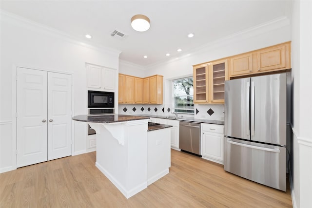 4444 Victory Dr Unit 26, Houston, TX 77088 - kitchen featuring stainless steel appliances, ornamental molding, light wood-type flooring, a kitchen breakfast bar, and a kitchen island