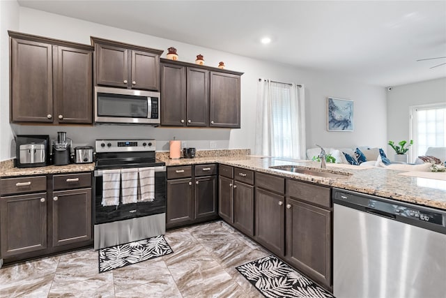10731 Spring Brook Pass Dr, Humble, TX 77396 - kitchen featuring stainless steel appliances, light marble finish flooring, dark brown cabinetry, light stone counters, and open floor plan