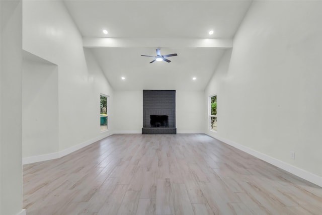 1602 Pine Oak Dr, Conroe, TX 77304 - unfurnished living room with beamed ceiling, healthy amount of natural light, ceiling fan, a brick fireplace, and light wood finished floors