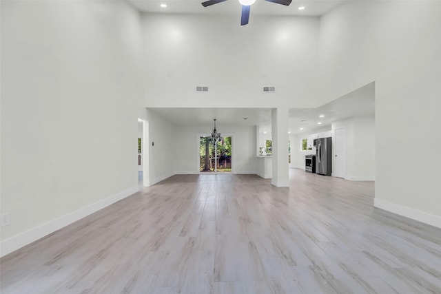 1602 Pine Oak Dr, Conroe, TX 77304 - unfurnished living room with ceiling fan, a high ceiling, a chandelier, recessed lighting, and light wood-style floors