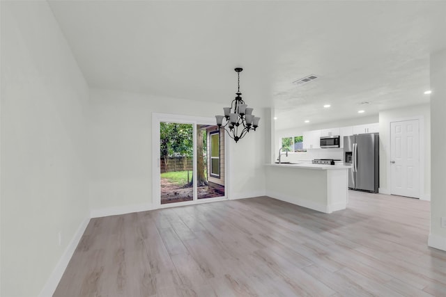 1602 Pine Oak Dr, Conroe, TX 77304 - unfurnished living room with a chandelier, light wood-style floors, and recessed lighting