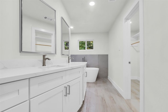 1602 Pine Oak Dr, Conroe, TX 77304 - bathroom with double vanity, a freestanding bath, wood finished floors, and recessed lighting