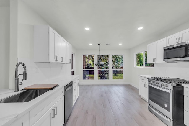 1602 Pine Oak Dr, Conroe, TX 77304 - kitchen with stainless steel appliances, recessed lighting, light countertops, white cabinetry, and light wood-style floors