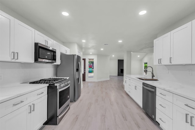 1602 Pine Oak Dr, Conroe, TX 77304 - kitchen featuring stainless steel appliances, white cabinetry, light wood-style floors, recessed lighting, and a peninsula