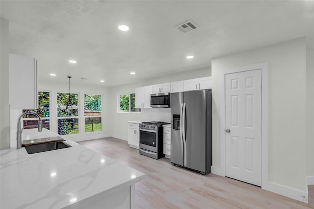 1602 Pine Oak Dr, Conroe, TX 77304 - kitchen featuring appliances with stainless steel finishes, white cabinets, light wood-style floors, recessed lighting, and light stone counters